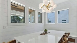 A modern dining area with a white marble table, wooden chairs, and a unique spherical chandelier. - The Gathering Place | Private Pool/Spa | Game Room | Rooftop Terrace (Santa Rosa Beach)
