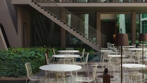 A modern outdoor dining area with round tables and chairs, a staircase, and a balcony with seating. - Central Retreat with Rooftop Swims and an Exclusive Light Display (Lisboa)