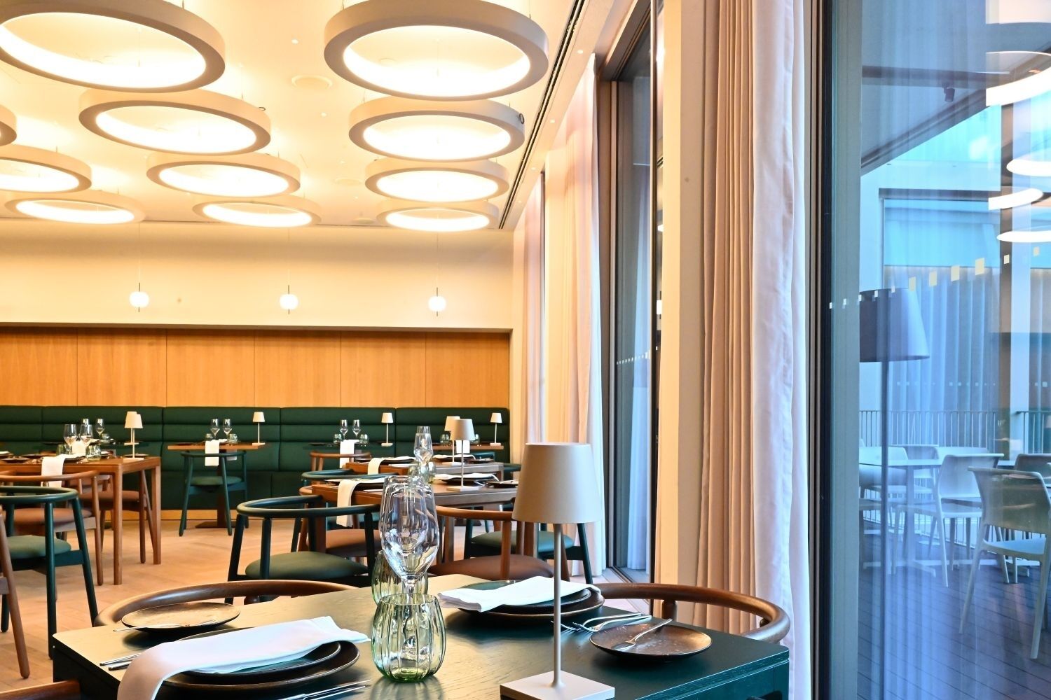 Un restaurant avec des luminaires ronds au plafond, des tables et des chaises en bois.