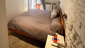 A bedroom with a bed, a nightstand, a window with curtains, and a view of the outside. - Designer apartment in Barcelona: Fully equipped 2-bedroom, the heart of the city (Barcelona)