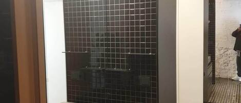 Un baño moderno con pared de azulejos negros, un lavamanos y un espejo.