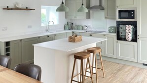 Una cocina moderna con una isla central, taburetes de bar y electrodomésticos integrados.