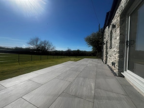 Un patio empedrado con un muro de piedra y cielo despejado.