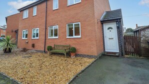 A two-story brick house with a white door and windows, a small front garden with gravel, and a wooden bench. - 2 Horseshoe Road (Montgomery)