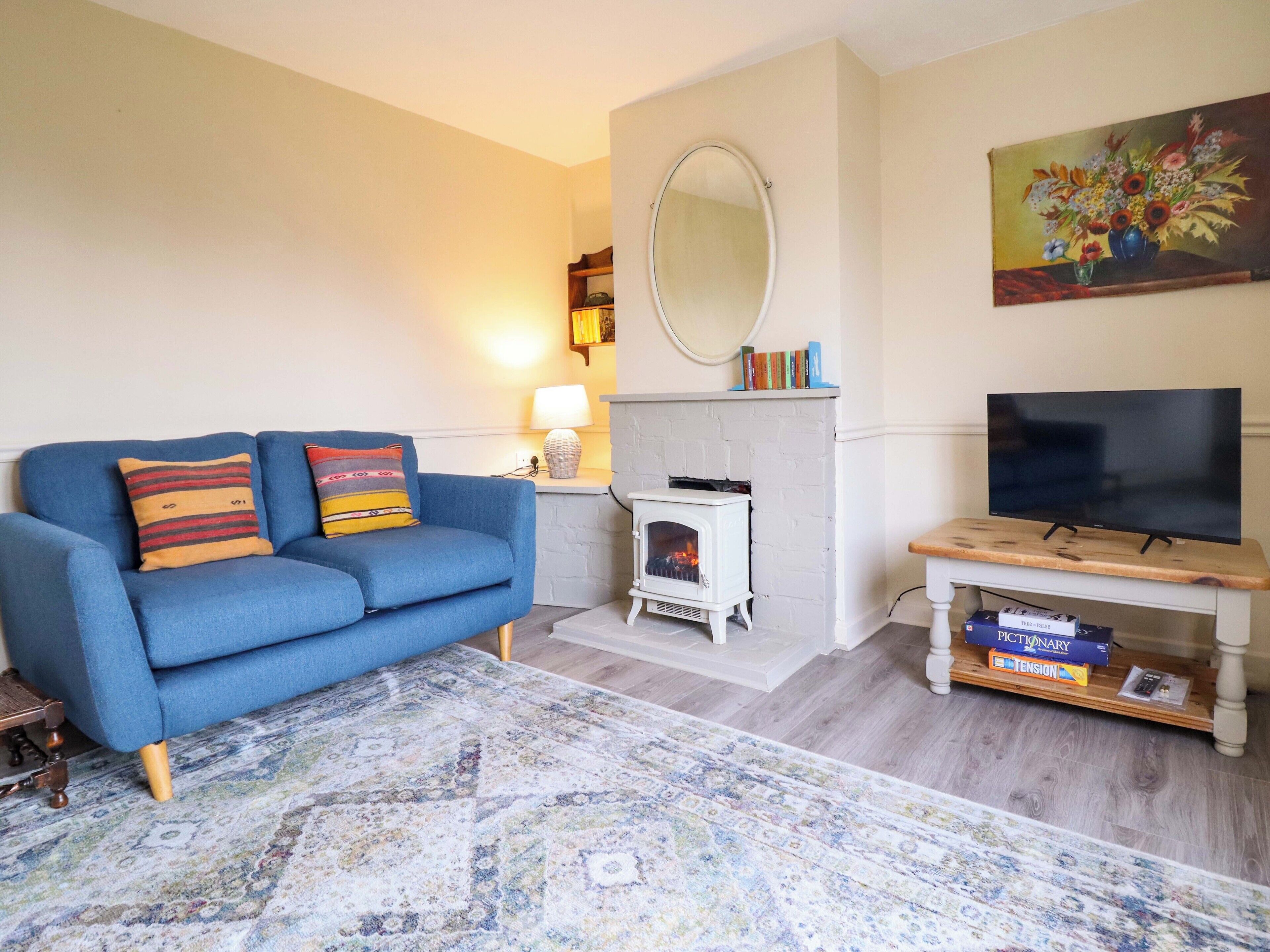 A living room with a blue sofa, a fireplace, a television, and a bookshelf.