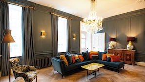 A spacious living room with a sectional sofa, a patterned armchair, a small coffee table, and a decorative cabinet.