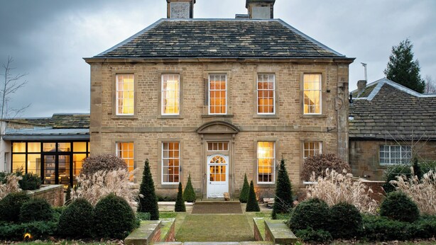 A large stone building with a symmetrical facade, multiple windows, and a central entrance.