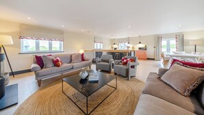 A spacious living room with a sofa, armchairs, a coffee table, and a dining area with a table and chairs. - Bell House (Amlwch)