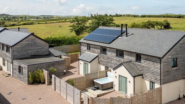 A modern house with solar panels, a hot tub, and a fenced garden. - Bell House (Amlwch)