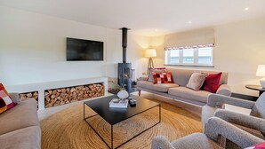 A modern living room with a fireplace, sofa, coffee table, and TV. - Bell House (Amlwch)