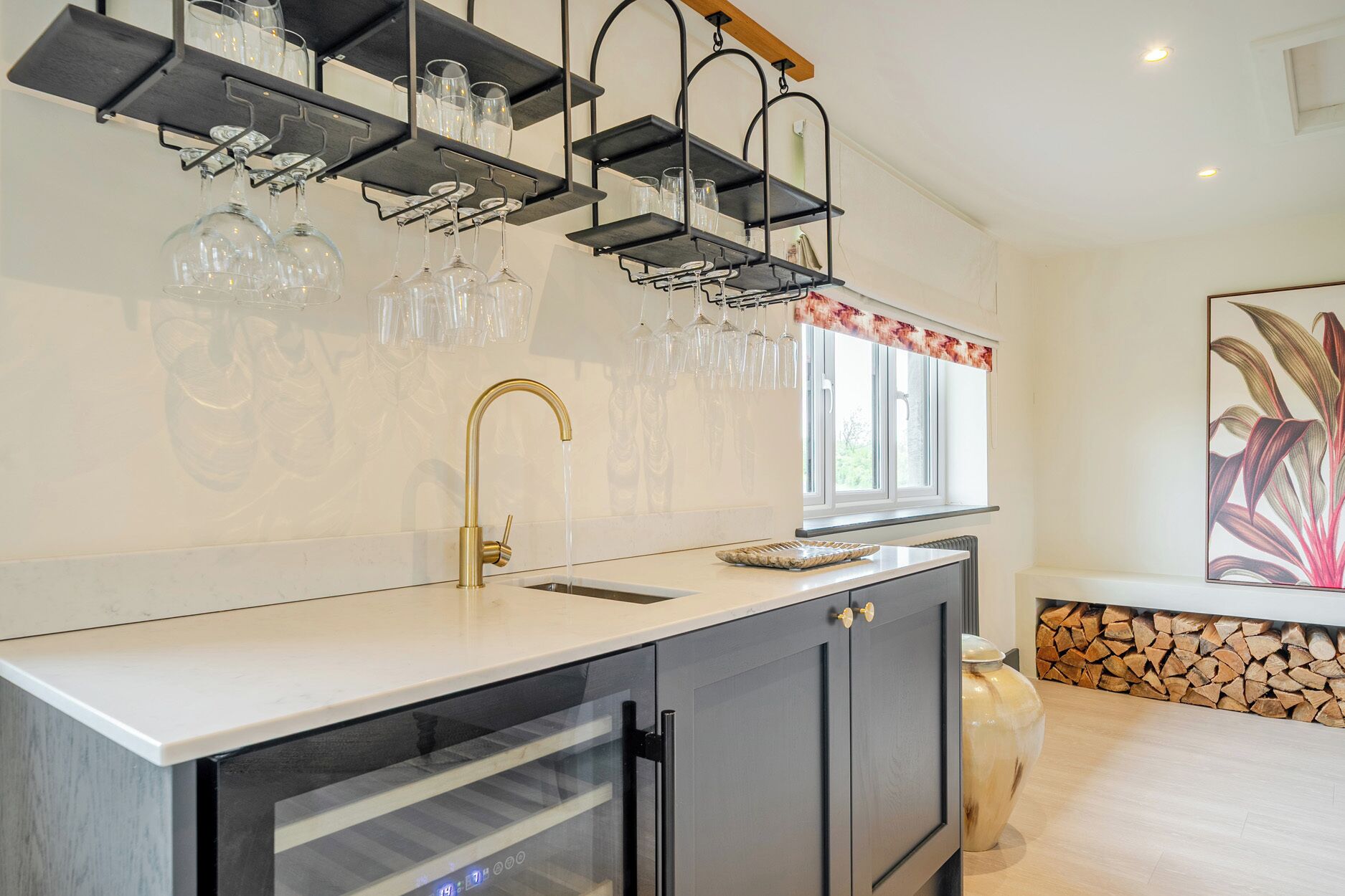 A kitchen with a built-in oven, a sink, and a wine rack above the counter.