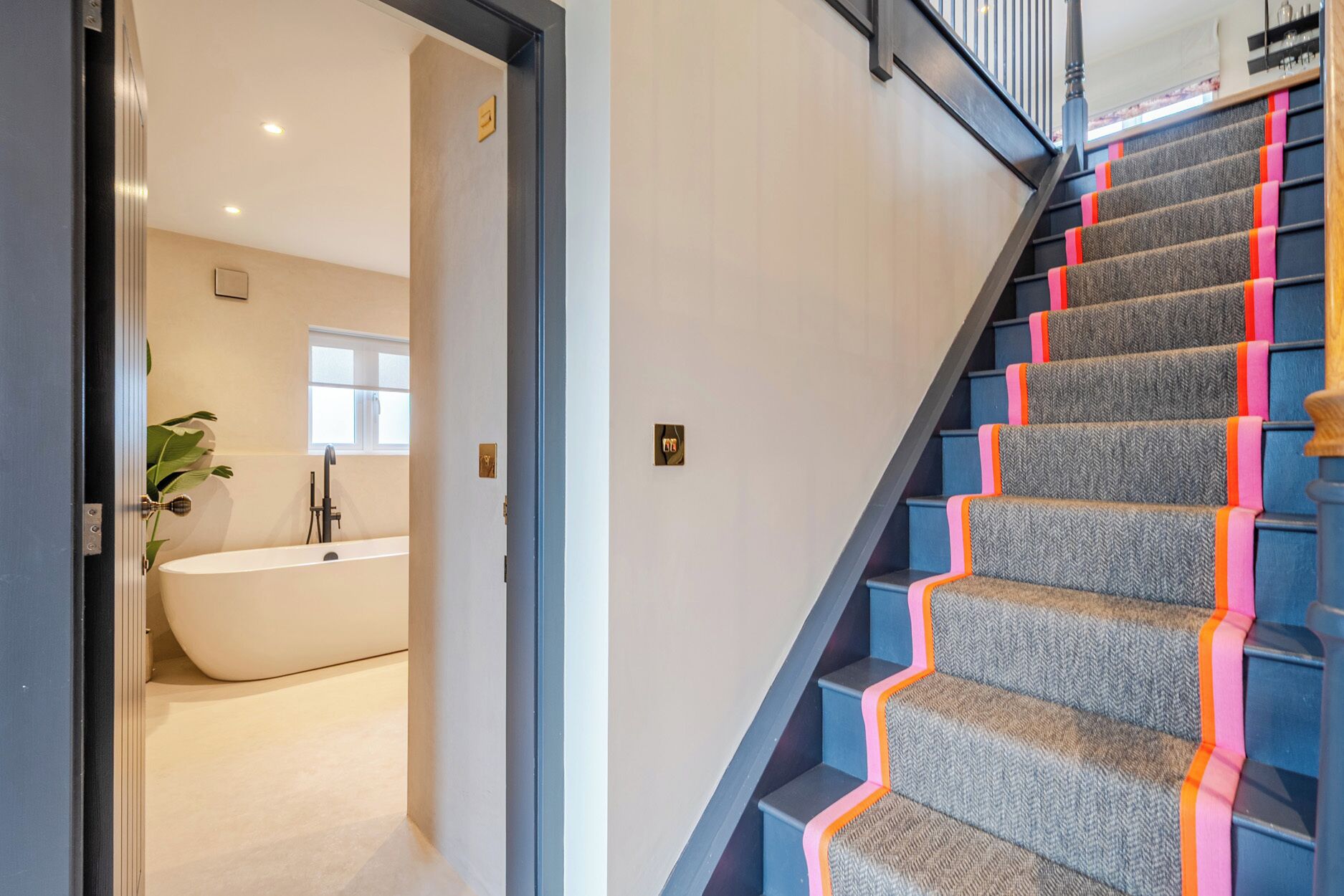 Un escalier au design moderne, une baignoire dans la pièce adjacente et un panneau de signalisation indiquant la sortie, bien visible.