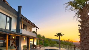 A modern house with a swimming pool, outdoor seating, and a view of the sunset. - ASİL VİLLA SAPANCA (Sapanca)