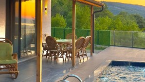 A modern outdoor pool area with a dining set and chairs, surrounded by a wooden deck and a glass wall. - ASİL VİLLA SAPANCA (Sapanca)