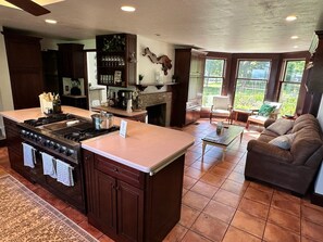 A kitchen with a large island, a dining area with a sofa, and a fireplace. - Spacious 6-bedroom house on Cayuga Lake in the heart of the Finger Lakes! (Ovid)