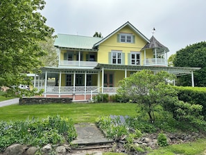 A two-story house with a balcony, a porch, and a stone pathway. - Spacious 6-bedroom house on Cayuga Lake in the heart of the Finger Lakes! (Ovid)