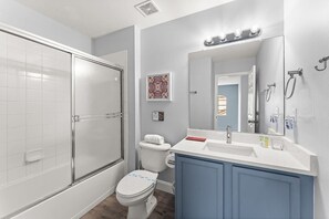 Een badkamer met een glazen douchecabine, een wit toilet en een wastafel met spiegel.