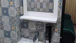 A bathroom with a white sink, a mirror, and patterned tiles. - The Royal Prince Hotel (Nawada)