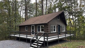 Une cabane avec une façade en bois, une véranda et un escalier menant à l’entrée.