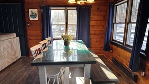 L’intérieur d’un chalet en bois, avec une table à manger, des chaises et un banc.