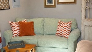 A living room with a light green sofa, two patterned pillows, a wooden coffee table, and a beige armchair. - The 1890 House @ Boone Docks- Log Cabin Getaway (Stillwater)