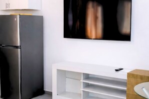 A modern kitchen with a stainless steel refrigerator, a white built-in oven, and a white console table with a glass top. - Cozy 1-bedroom beachfront apartment in peaceful Playa Juan Dolio with AC (Playa Juan Dolio)