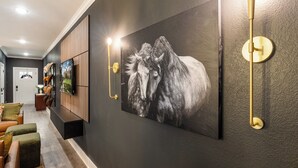 A hallway with a large black and white horse painting on the wall, a wooden cabinet, and a modern light fixture. - Modern 4BR Ensuite Townhome Near Texas A&M (College Station)