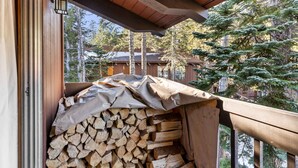 A stack of firewood under a covered area with a wooden railing and a lantern. - 2BR Overlooks Shared Pool, Near Gondola & Village! (Mammoth Lakes)
