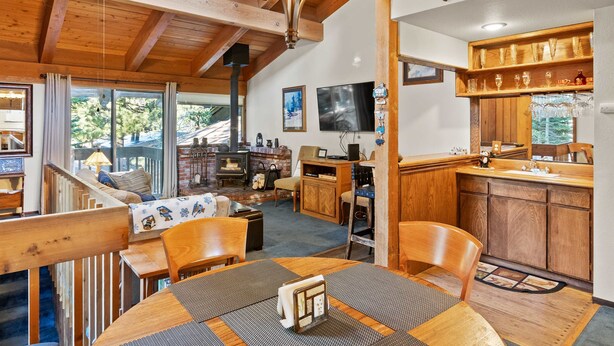 A cozy interior with a wooden dining table, chairs, a fireplace, and a kitchen area with wooden cabinets and a countertop. - 2BR Overlooks Shared Pool, Near Gondola & Village! (Mammoth Lakes)