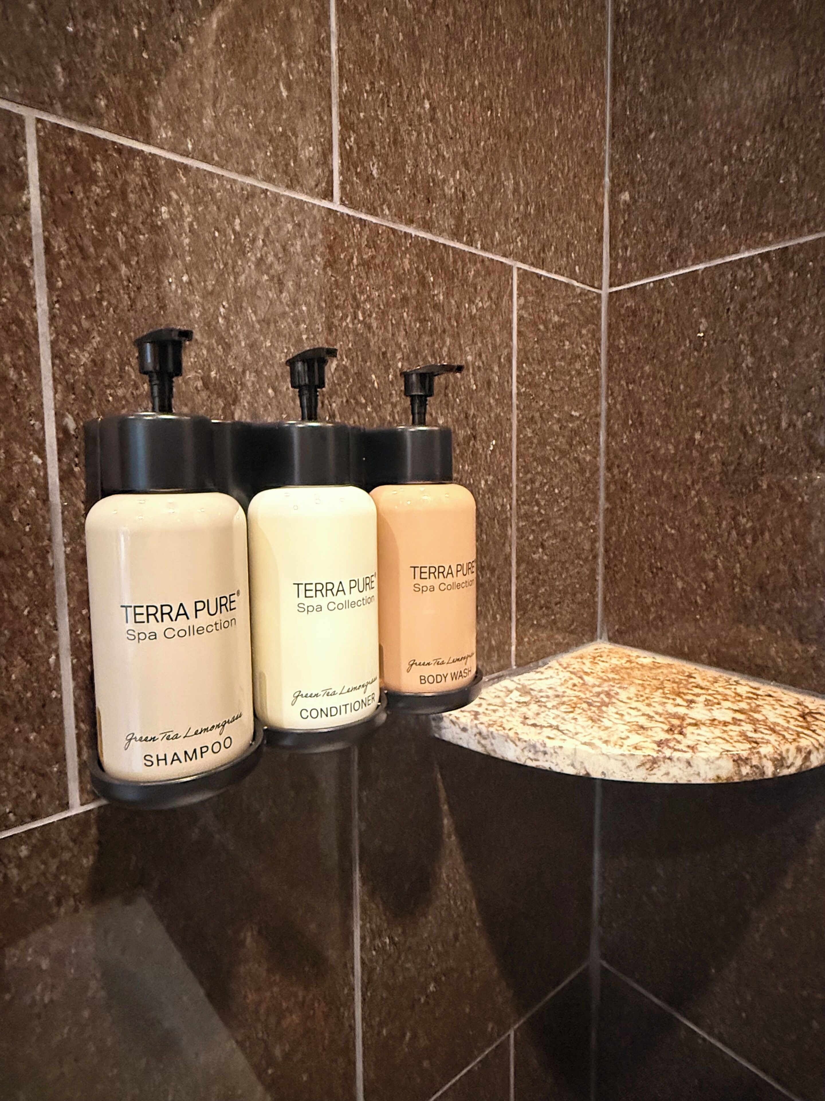 Three bottles of Terra Pure Spa Collection products on a tiled wall.