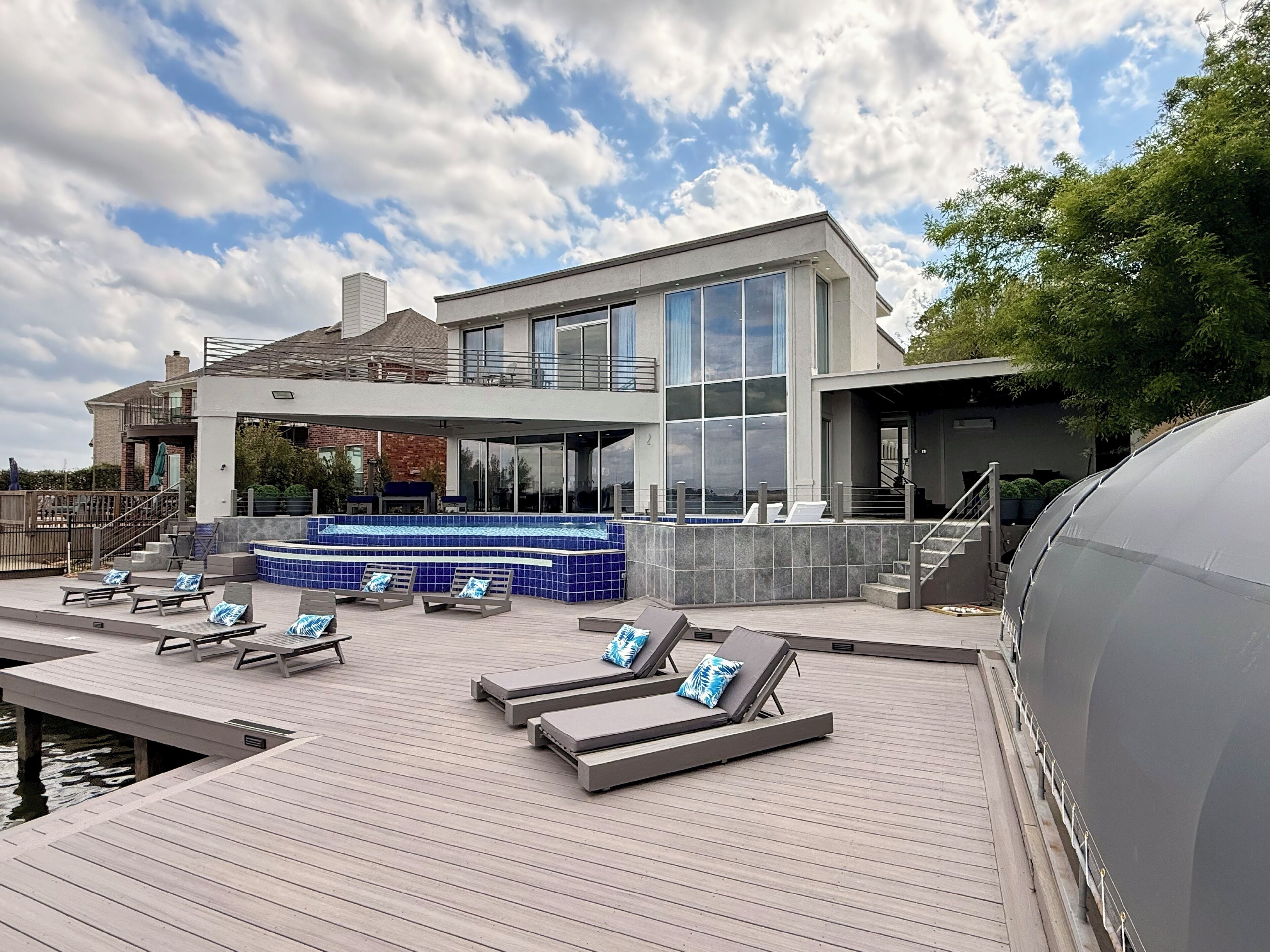 A modern outdoor pool area with lounge chairs and a hot tub.