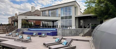 A modern outdoor pool area with lounge chairs and a hot tub.