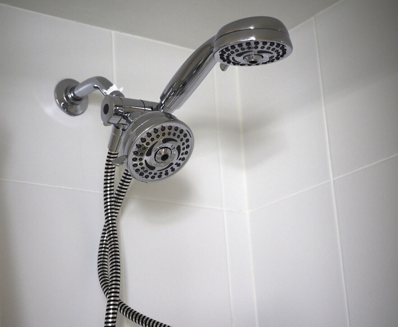 Een douche met een handdouche en een flexibele slang.