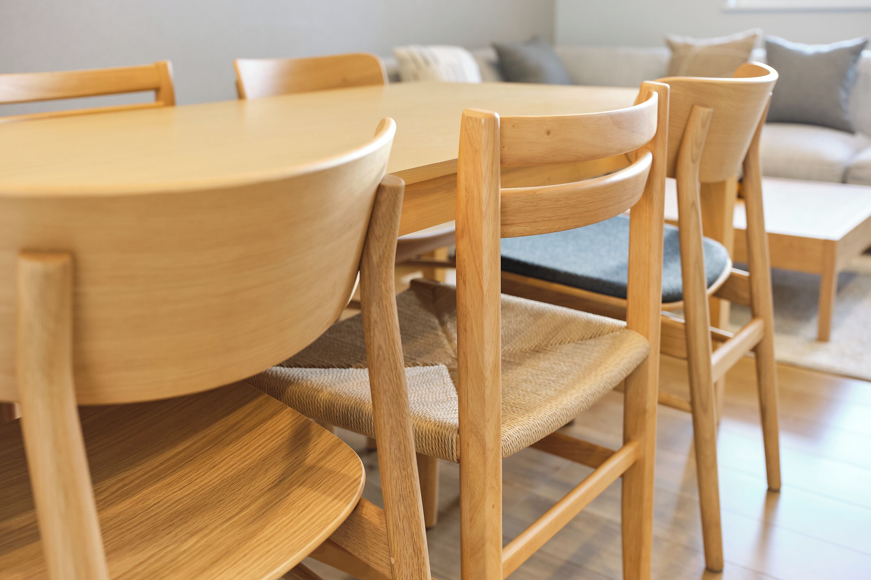 A wooden dining table with chairs, a sofa, and a small coffee table in a living room.