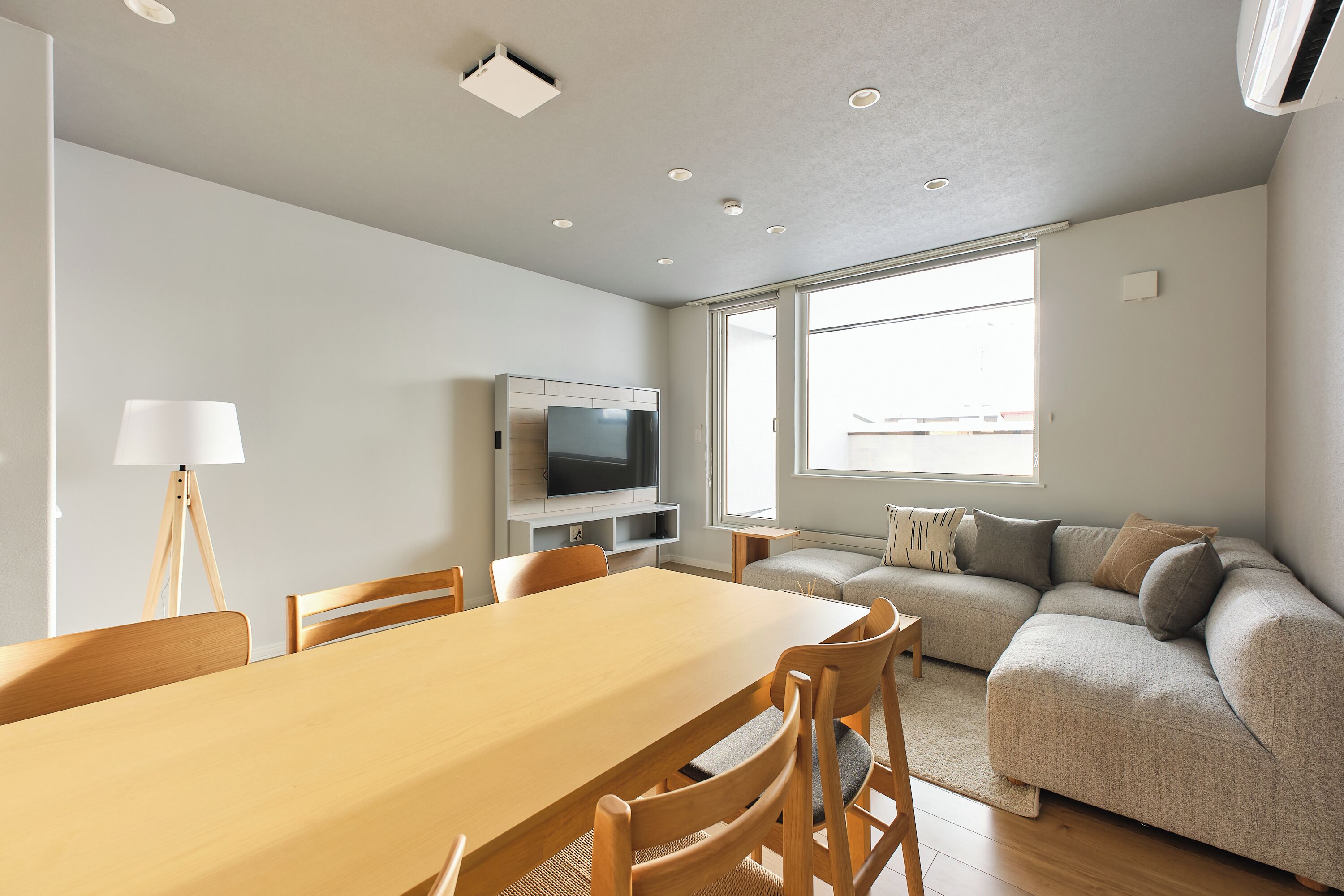 Ein modernes Wohnzimmer mit Esstisch, Sofa und Fernseher.