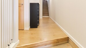 A narrow hallway with wooden flooring, a black cabinet, and a staircase at the end. - Higashikawa Hinna (Higashikawa)