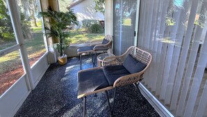 Un patio couvert aménagé avec des meubles en osier et une plante en pot.