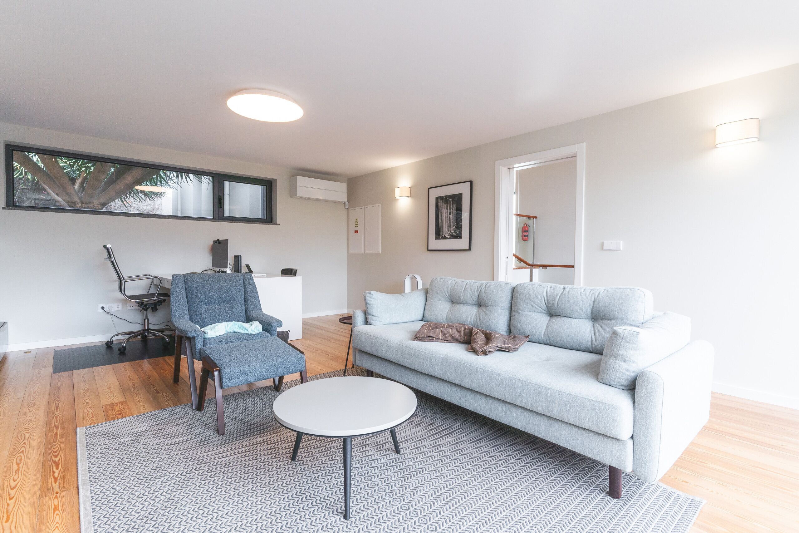 A modern living room with a grey sofa, a round coffee table, and a blue armchair.