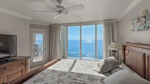 A hotel room with a bed, a television, a ceiling fan, and a view of the ocean. - Big August Discounts! Spacious 3BR Oceanfront Unit W/Free Beach Chair Service (Panama City Beach)