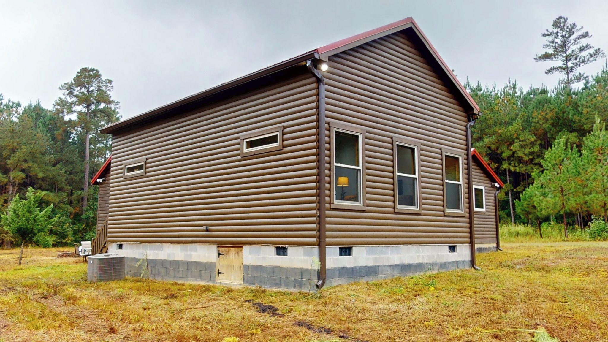 A two-story log cabin with a gabled roof, a front porch, and a small attached garage.