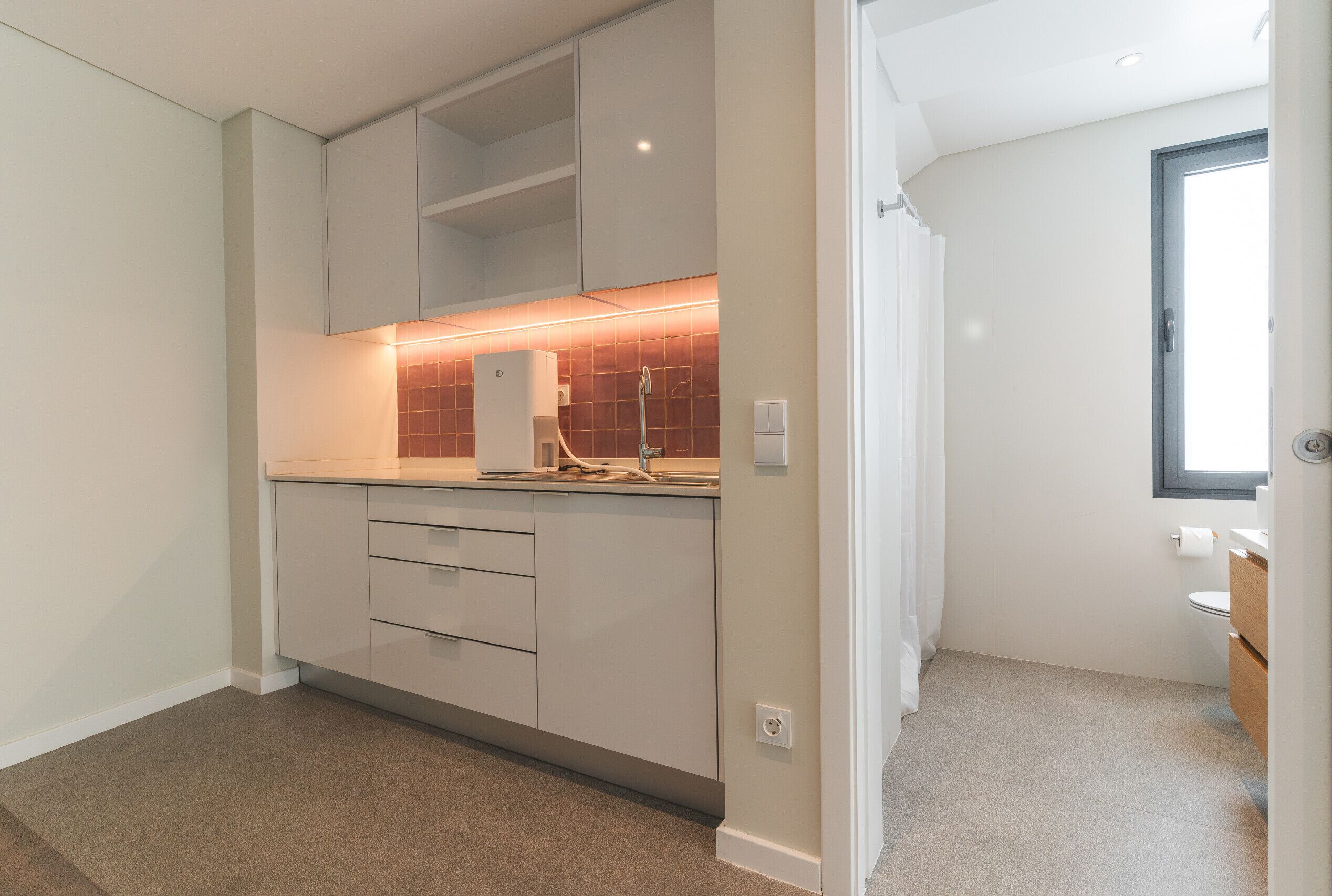 A modern kitchen with white cabinets, a countertop, and a backsplash.