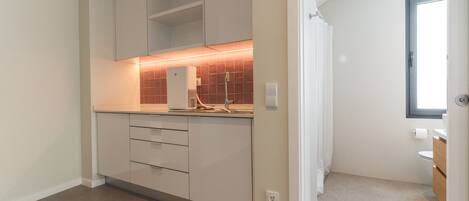 A modern kitchen with white cabinets, a countertop, and a backsplash.
