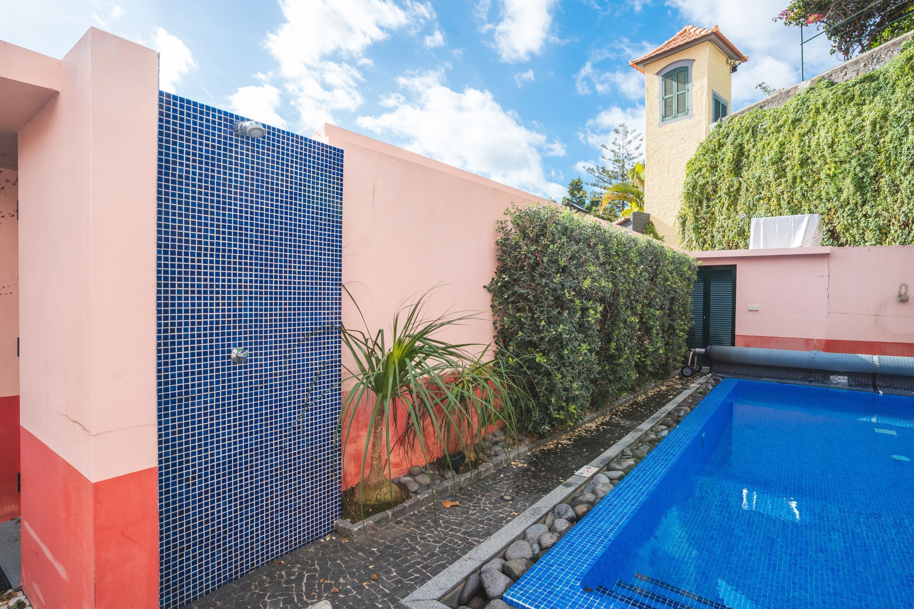 A swimming pool adjacent to a building with a tiled facade and a small tower.