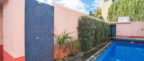 A swimming pool adjacent to a building with a tiled facade and a small tower.