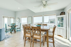 A dining area with a large table and chairs, a ceiling fan, and a view of the balcony. - Beachfront Beauty w/ Wraparound Deck & Private Dune Walkover (Galveston)