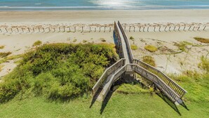 Une promenade en bois qui mène à une plage offrant une vue dégagée sur l’océan.