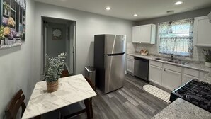 A modern kitchen with a marble countertop, stainless steel appliances, and a wooden floor. - Ranch Cozy Home close to O'Hare (River Grove)