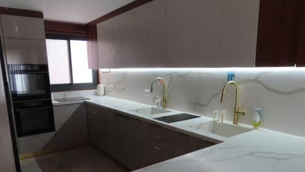 A modern kitchen with white marble countertops, two sinks, and a built-in oven. - stunning appartment in jerusalem romema (Jerusalem)