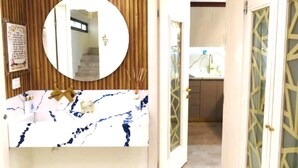 A bathroom with a marble sink, a round mirror, and a wooden panel wall. - stunning appartment in jerusalem romema (Jerusalem)