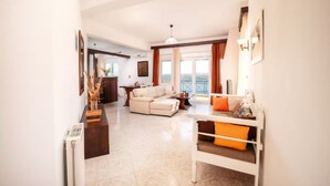 A spacious living room with a sofa set, a coffee table, and a dining area with a table and chairs. - Aptera Dream Apartment (Souda)